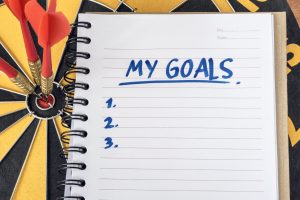 Words my goals on notebook with three darts on bullseye target in dartboard background